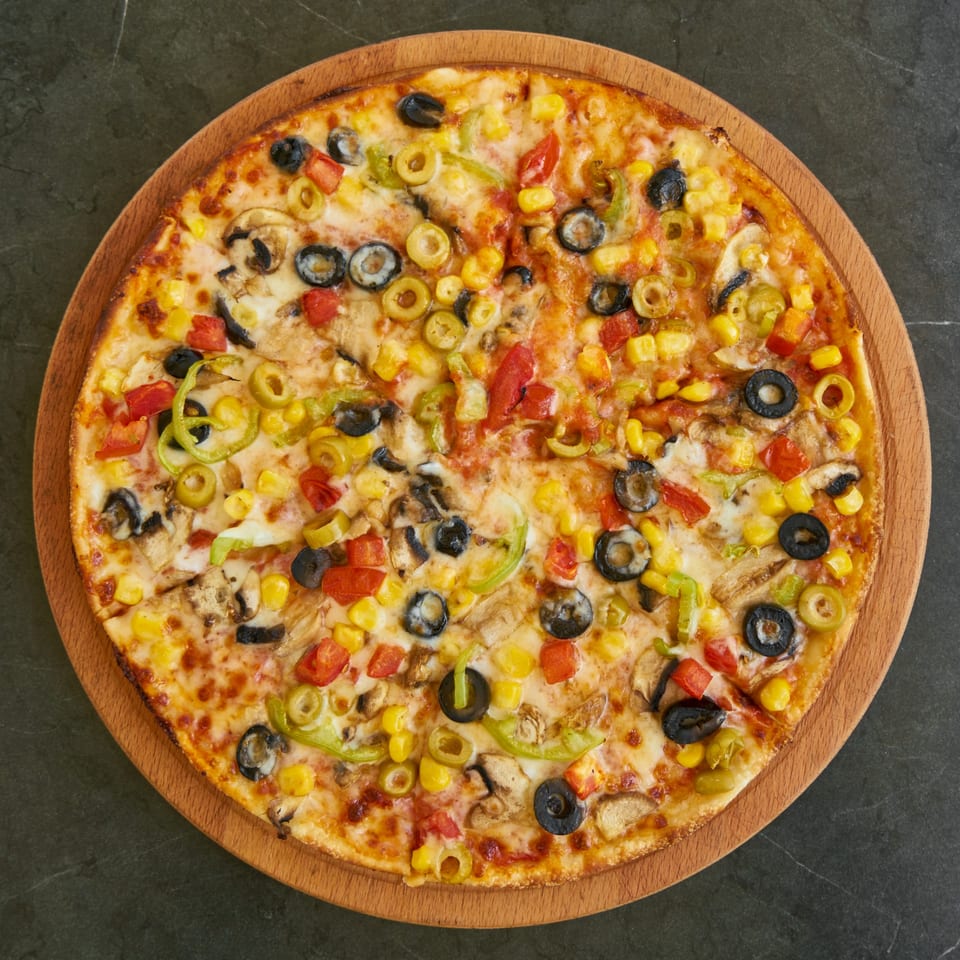 Guido's Pizza & Pasta's vegetarian pizza, topped with olives, corn, mushrooms, and bell peppers.